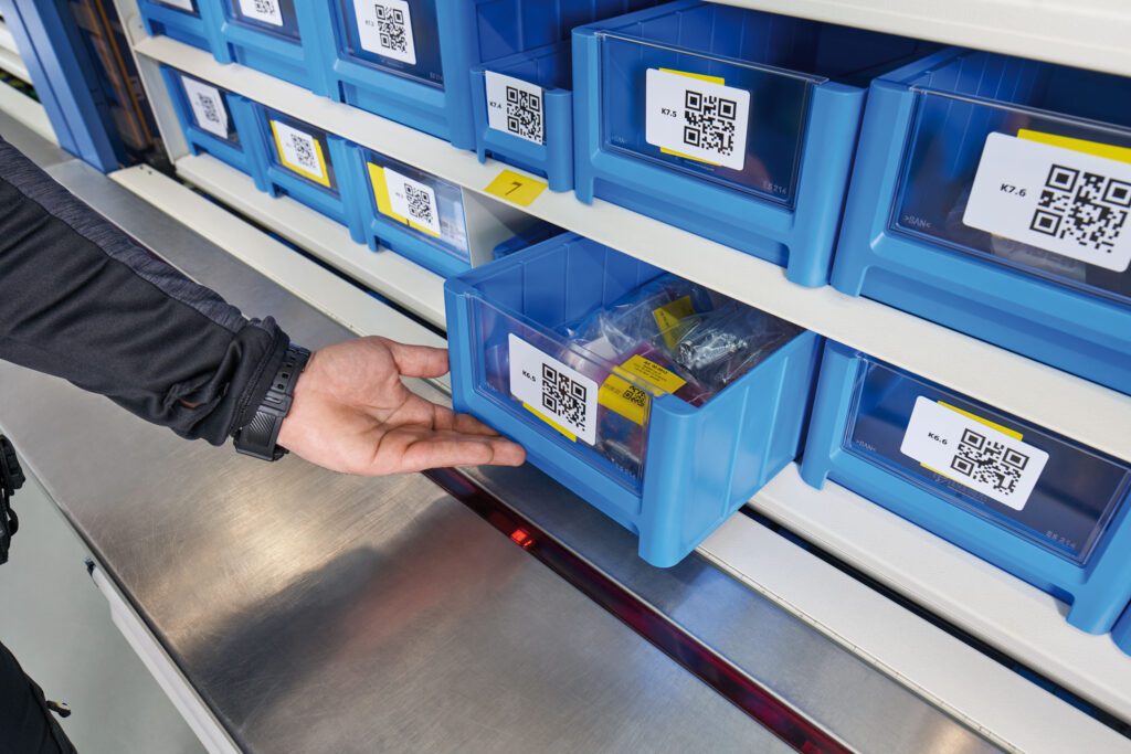 Operador a realizar picking de peças pequenas em sistema de armazenamento automatizado com códigos QR